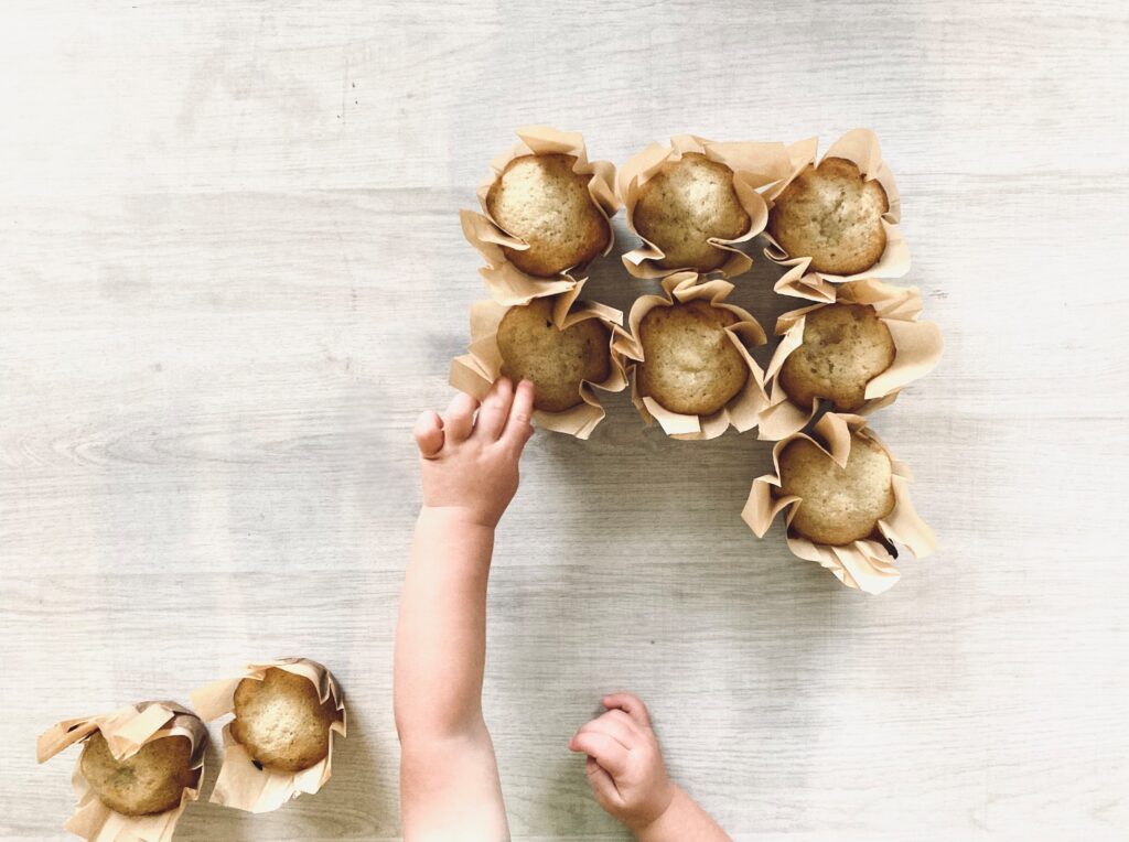 little hands taking muffins from a table